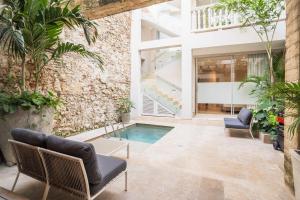un cortile interno con piscina e sedie di Casa Catalina De Mokana By SoHo a Cartagena de Indias