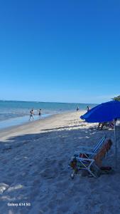 a beach with a chair and an umbrella and people on the beach at Suite privativa santinho in Porto Seguro +4 photos