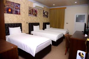 a hotel room with two beds and a desk at Diana Palace Hotel in Diyānah
