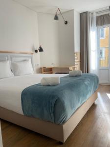a bedroom with a large bed with a blue blanket on it at Bacalhoeiros 125 Hotel in Lisbon