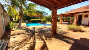 a patio with a swimming pool and palm trees at Recanto da Família in Quadra