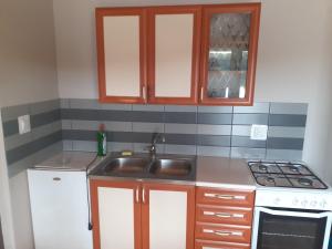 eine Küche mit Spüle und Herd in der Unterkunft Domki nad jeziorem i pod lasem in Zdbice + 114 Fotos