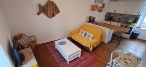 Una sala de estar con un sofá amarillo y una mesa. en Le Gîte de l'Amer - T2 - Duplex - Centre Bourg, en Baden