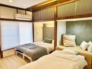東京にある和みの宿Rent the whole houseのベッド2台と窓のある寝室
