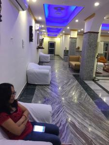 a woman sitting on a couch in a waiting room at Gautama Hotel in Khajurāho