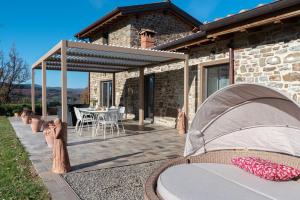 a stone house with a patio with a table at Villa Lux Poggelleri vista unica sul Casentino in Poppi