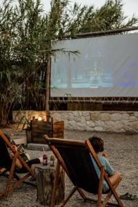 two women sitting in lawn chairs in front of a screen at Ergon Beach House Nikiti in Nikiti