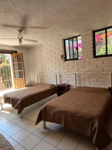 ein Schlafzimmer mit zwei Betten und einer Ziegelwand in der Unterkunft Casa de los ángeles en el centro in Malinalco