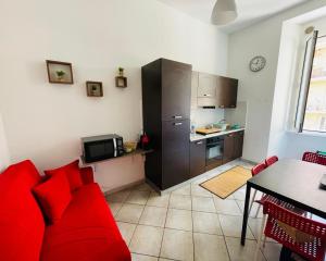a living room with a red couch and a kitchen at Volupta’s house Trastevere in Rome