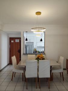 uma sala de jantar com uma mesa e cadeiras brancas em apartamento em edifício de frente para o mar na praia do morro Guarapari em Guarapari