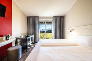 a hotel room with two beds and a desk and a window at Hotel Irschenberg Süd in Irschenberg