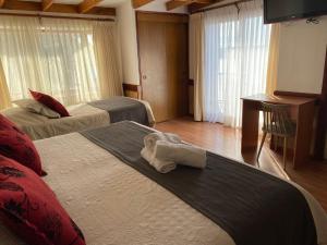 a hotel room with two beds with towels on the bed at Hotel Encanto del Río in Valdivia