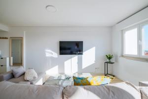 a white living room with a couch and a table at Sunset Horizon Carcavelos in Carcavelos
