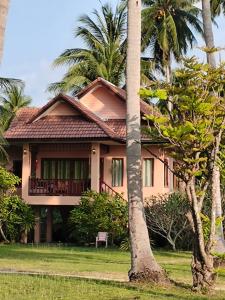 a house with palm trees in front of it at Links Sunset Beach House in Amphoe Koh Samui
