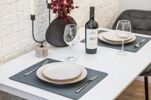a table with plates and glasses and a bottle of wine at Comfortable Living- Free Coffee, Netflix & More - GrandStay md in Chişinău