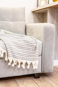 a gray couch with a white crochet blanket on it at Comfortable Living- Free Coffee, Netflix & More - GrandStay md in Chişinău +25 photos