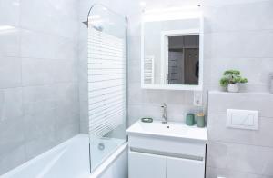 a white bathroom with a sink and a shower at Comfortable Living- Free Coffee, Netflix & More - GrandStay md in Chişinău