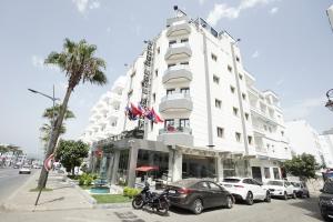 a white hotel with cars parked in front of it at Hotel nord kap in M'diq