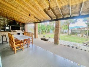 un patio con mesa, sillas y una ventana grande en Casa na Praia e Campo, en Garopaba