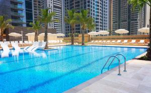 a large swimming pool with chairs and umbrellas at Cosy Apartment Marina Gate in Dubai