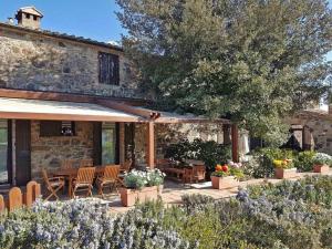 Un patio con sillas y mesas y un edificio. en Cottage Le Ginestre con piscina in Val d'Orcia, en Radicofani