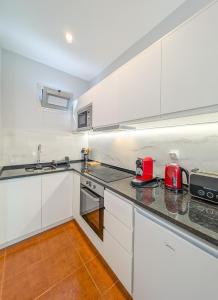 a kitchen with white cabinets and red appliances at Casas das Hortas, Studio Vista Jardim e Serra in Seixal
