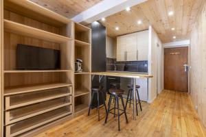 Una cocina con muebles de madera y una barra con taburetes. en Résidence Les Crêts 1 - Val-d'Isère, en Val dʼIsère