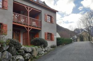 a white building with a stone wall and a street at Studio vue montagnes RDC piscine in Cauterets