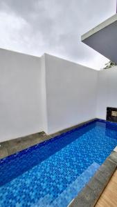 una piscina en una habitación blanca con azulejos azules en SERENA Villa, en Batu