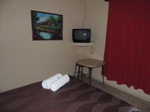 um quarto com uma cama, uma pequena mesa e uma televisão em Hacienda Cañada Rica 2 em Ciudad Madero