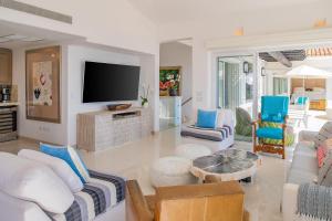 a living room with white furniture and a flat screen tv at Villa Esencia Del Mar in Cabo San Lucas