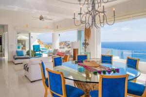 a dining room with a glass table and blue chairs at Villa Esencia Del Mar in Cabo San Lucas