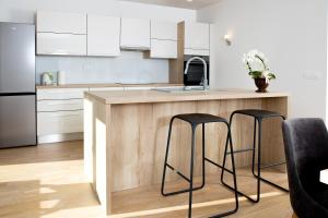 a kitchen with white cabinets and a counter with stools at DALGONA apartma Godler, Podčetrtek in Podčetrtek