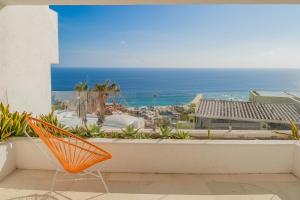 an orange chair sitting on a balcony looking out at the ocean at Villa Esencia Del Mar in Cabo San Lucas