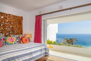 a bedroom with a bed and a large window with the ocean at Villa Esencia Del Mar in Cabo San Lucas +46 photos