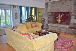a living room with a yellow couch and a fireplace at Country House La Feronnière in Le Mesnil-Amand