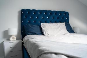 a bed with a blue headboard and a night stand at The luxe by Viennese Aparts 2 Bedroom! in Bradford