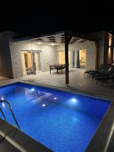 einen Pool in der Nacht mit einem Tisch und Stühlen in der Unterkunft Villa Teuta in Kaštel Stari