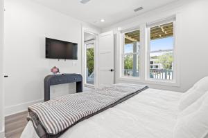 ein weißes Schlafzimmer mit einem Bett und einem Flachbild-TV in der Unterkunft NEW Orchards Ocean in Oak Island, Custom home with private heated pool in Oak Island
