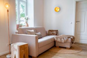 una sala de estar con un sofá y un taburete en Ferienhof Taarstedt Udo, en Taarstedt