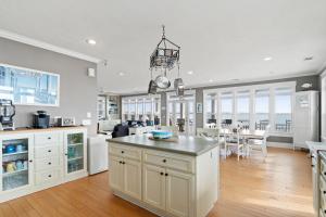a kitchen with white cabinets and a dining room with a table at Experience luxury at On The Rocks, spacious 4 bedroom retreat with private pool! in Ocean Isle Beach