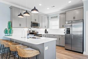 a kitchen with white cabinets and a stainless steel refrigerator at Experience luxury at Notorious OIB, a spacious 4 bedrooms, 4 baths, perfect for up to 10 guests in Ocean Isle Beach