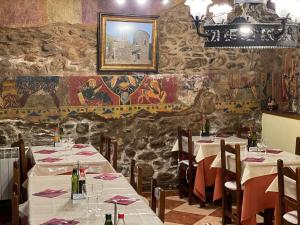 a restaurant with tables and chairs in a room with a stone wall at Hostal Rusó SC in Llivia