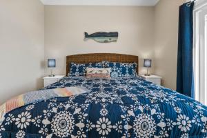 a bedroom with a blue and white bed with two windows at Coastal Sunset - private heated pool, spa, close walk to the beach in Ocean Isle Beach +42 photos