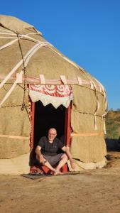 a man sitting in the doorway of a igloo at Desert Dream Yurt Camp in Nurota