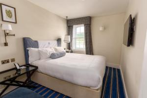 una camera da letto con un grande letto bianco e una finestra di The Relais Henley a Henley on Thames