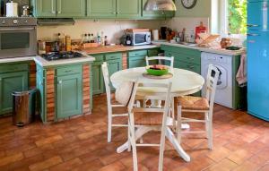 a kitchen with green cabinets and a table and chairs at Lovely Home In Canville Les Deux Égli in Canville-les-Deux-Églises