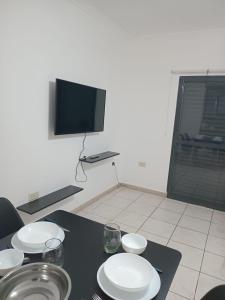 a table with white plates and a television on a wall at Centro de Paraná - 1 Dormitorio !!! in Paraná +4 photos