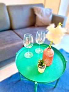 a green table with three wine glasses and a plant on it at Apartments C'EST LA SEA - Whirlpool-Suite oder Dachterrassen-Suite - Pets welcome in Neusiedl am See