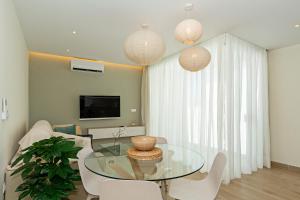 プエルト・デル・カルメンにある2BR Memela Dream Home - Modern & Seaviewsのリビングルーム(ガラステーブル、白い椅子付)